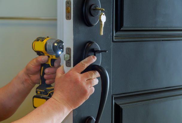 closeup of a professional locksmith installing a new lock on a house exterior door with the inside
