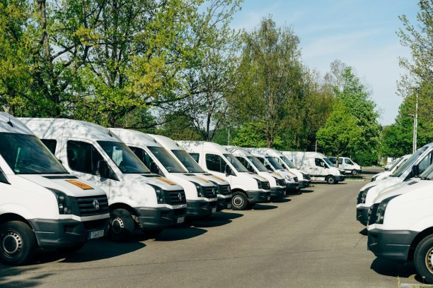Row of white fleet vans parked at a depot